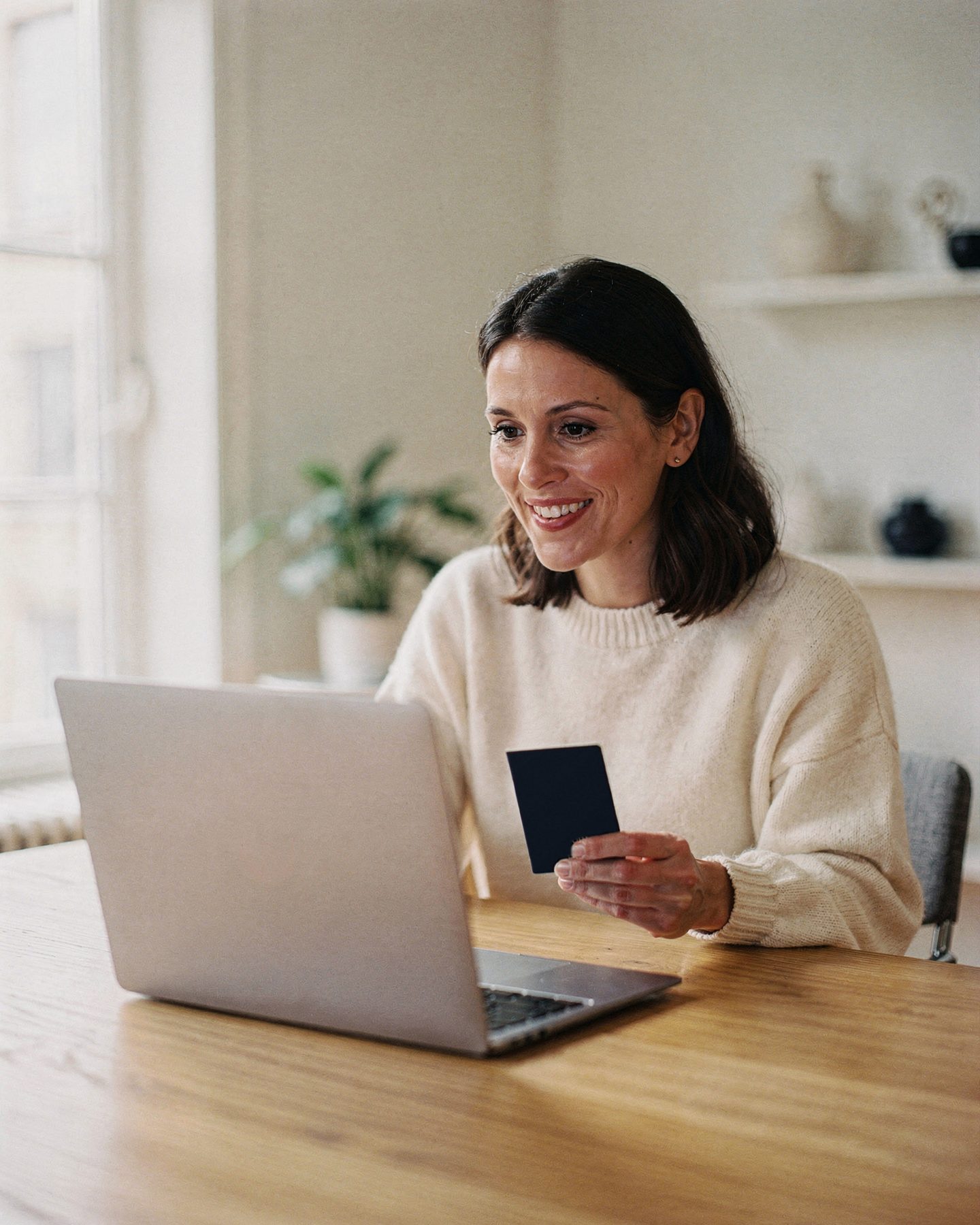 A woman at her laptop holding a passport